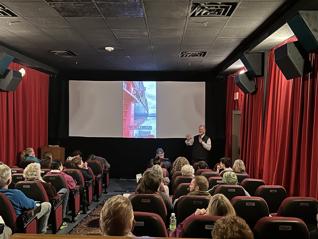 A man gives a presentation to an audience in a theater.