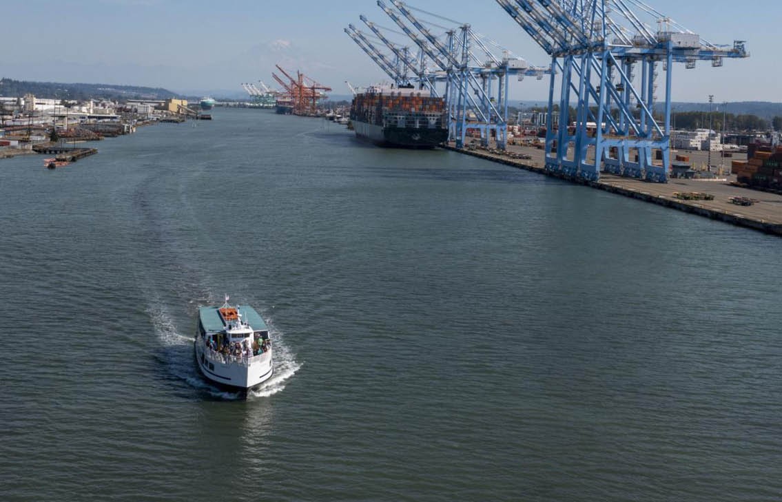 A Port of Tacoma boat tour - a passenger ferry moves through a waterway near container cranes.
