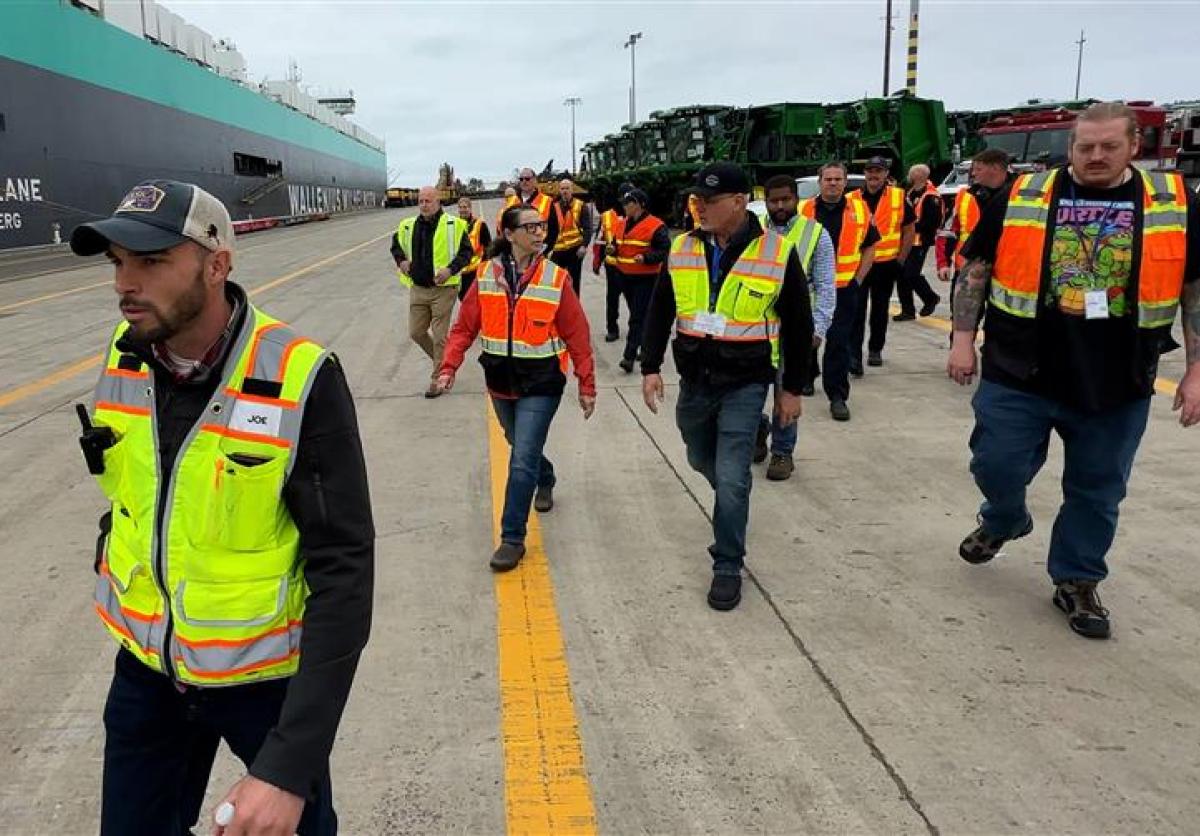 A group of people in construction vests walk through a terminal.